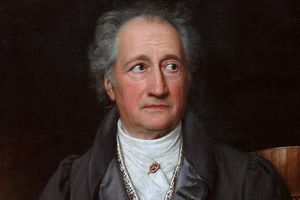 Portret dojrzałego mężczyzny z siwymi włosami, w ciemnym płaszczu, z poważnym wyrazem twarzy.