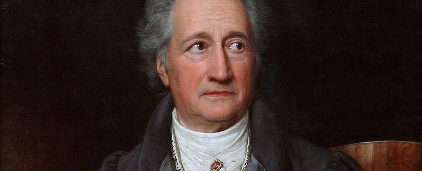 Portret dojrzałego mężczyzny z siwymi włosami, w ciemnym płaszczu, z poważnym wyrazem twarzy.