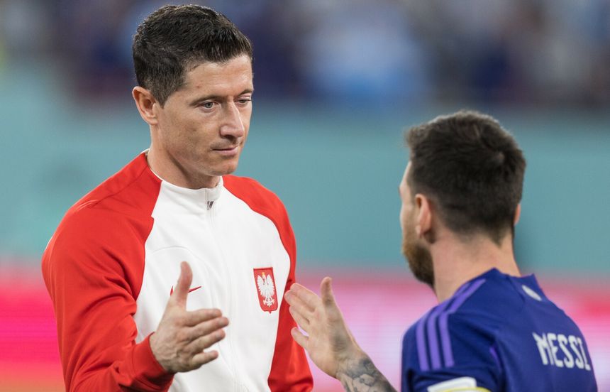Na zdjęciu Robert Lewandowski w białej bluzie z czerwonymi akcentami, rozmawia z Lionelem Messim.