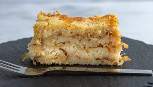 Aperitif na czarnym talerzu - kawałek ciasta jabłkowego z chrupiącą skórką i widelcem obok.