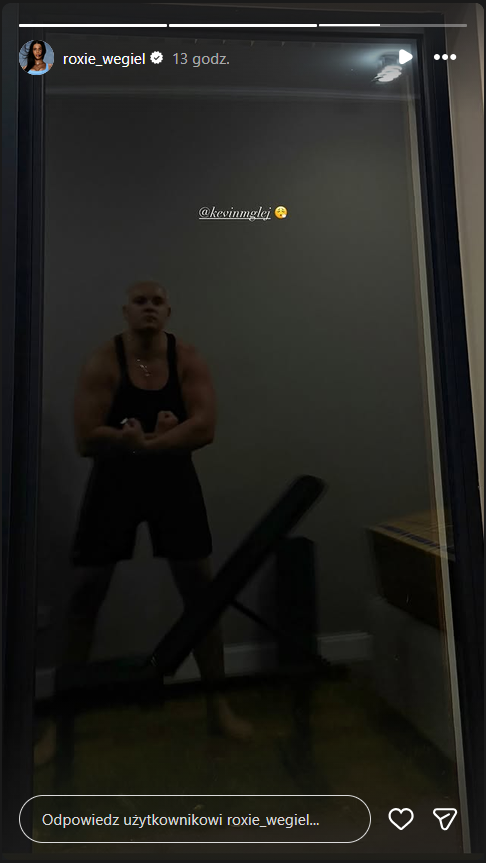 Kevin Mglej w ciemnym stroju sportowym, prezentujący muskulaturę w odbiciu.