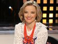Kobieta z krótkimi, blond włosami, uśmiecha się i nosi kolorową biżuterię.