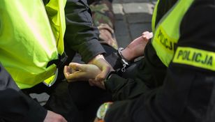 Policjant zakłada kajdanki.