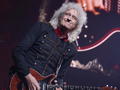 Brian May w czarnej kurtce i z czerwoną gitarą podczas koncertu