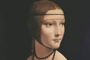 Portret kobiety w ciemnej sukni z naszyjnikiem, z delikatnym uśmiechem i jasnym tłem.