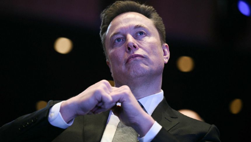 Na zdjęciu mężczyzna w garniturze z gestem dłoni, w tle rozmyte światła.