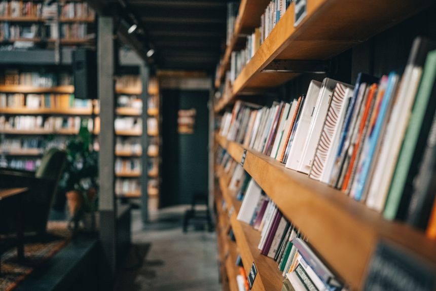 Wnętrze biblioteki z regałami pełnymi książek i wygodnym fotelem w tle.