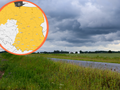 Na zdjęciu widok na zielone pole i drogę pod ciemnymi chmurami. W tle mapa Polski z zaznaczonym obszarem.