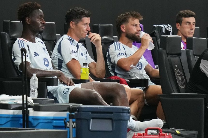 Czterech piłkarzy w niebieskich strojach siedzi na ławce rezerwowych, wśród nich Robert Lewandowski.
