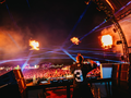 DJ grający na scenie podczas Sunrise Festival 2025, z efektem świetlnym i ogniami w tle.