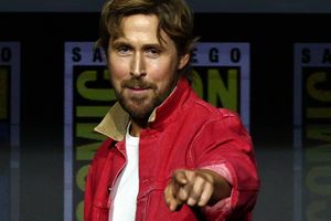 Mężczyzna w czerwonej kurtce wskazuje palcem, uśmiechając się do kamery. Tło z logo Comic-Con.
