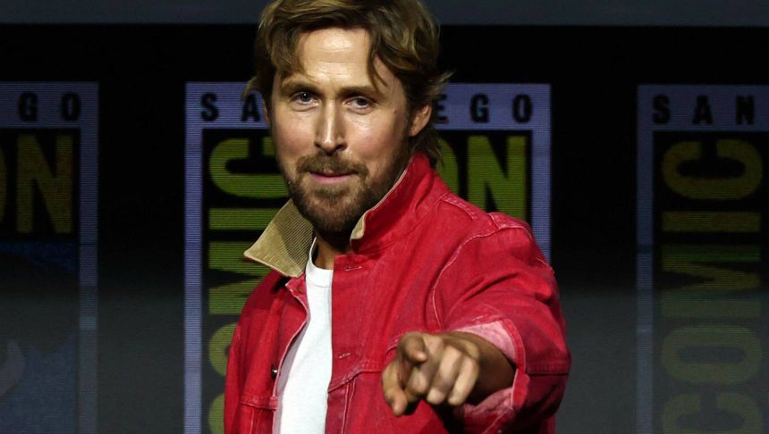 Mężczyzna w czerwonej kurtce wskazuje palcem, uśmiechając się do kamery. Tło z logo Comic-Con.