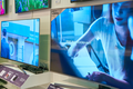 Zestaw telewizorów na ścianie w sklepie, z wyraźnymi ekranami i informacjami o modelach.