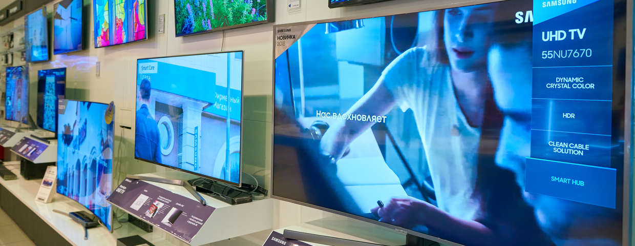 Zestaw telewizorów na ścianie w sklepie, z wyraźnymi ekranami i informacjami o modelach.