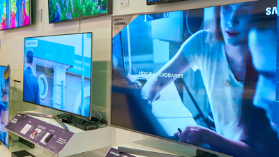 Zestaw telewizorów na ścianie w sklepie, z wyraźnymi ekranami i informacjami o modelach.