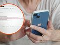 Kobieta trzyma telefon i przegląda dokumenty na ekranie. W tle niewyraźne przedmioty domowe.