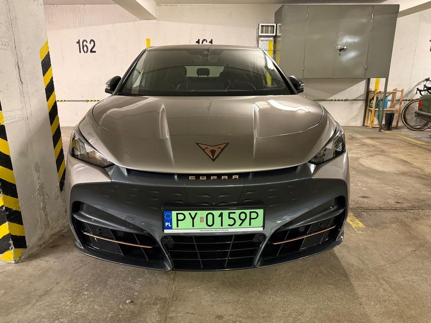 Nowoczesny samochód marki Cupra, stojący na parkingu, z widocznym numerem rejestracyjnym.
