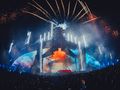 Kolorowa scena festiwalowa z fajerwerkami, tłum ludzi podziwiający występ.