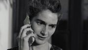 Kobieta mówi przez telefon, wygląda na zmartwioną, z krótkimi, falowanymi włosami.