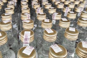 Zbliżenie na rząd szklanych butelek z złotymi zakrętkami i etykietami.