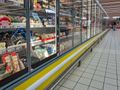 Widok półki z lodówkami w sklepie, pełnymi różnorodnych serów i produktów mlecznych.