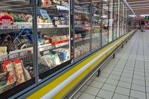 Widok półki z lodówkami w sklepie, pełnymi różnorodnych serów i produktów mlecznych.