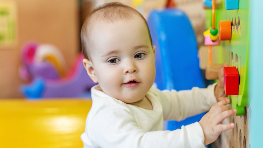 Dziecko bawi się na placu zabaw z kolorowymi elementami do chwycenia i manipulacji.