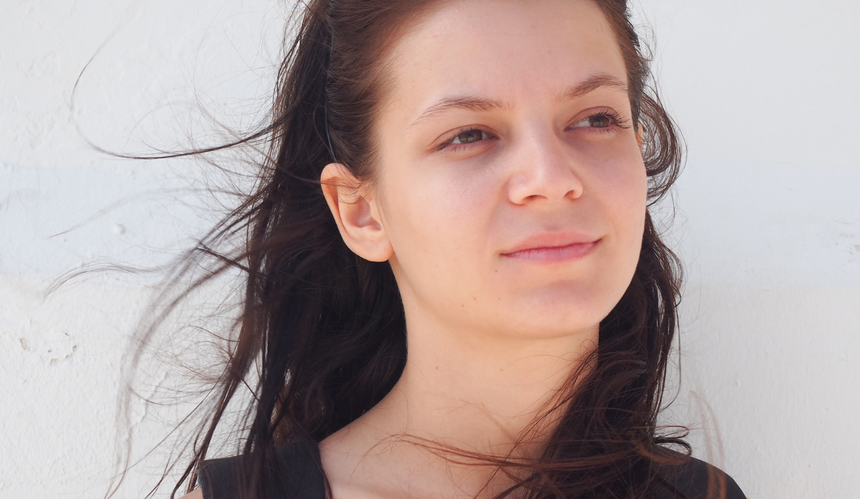 Zamyślona brunetka na tle białej ściany