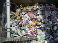 Obrazek przedstawia stos pomiętych opakowań, w głównej mierze plastikowych, w kontenerze.