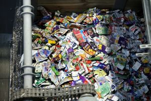 Obrazek przedstawia stos pomiętych opakowań, w głównej mierze plastikowych, w kontenerze.