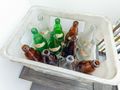 Kosz z pustymi butelkami w różnych kolorach: brązowe, zielone i przezroczyste.