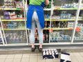 Pracownik sklepu stoi przed wystawą lodówek, sięgając po produkty z półki.
