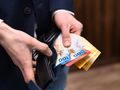 Mężczyzna trzyma skórzany portfel z banknotami o różnych nominałach.