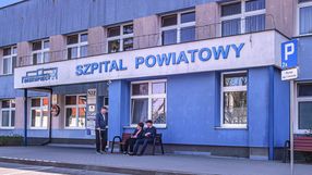 Na zdjęciu widoczny jest budynek szpitala powiatowego oraz kilka osób przed wejściem.