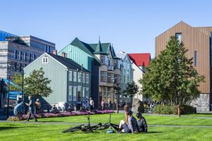 Kolorowe budynki w Reykjaviku, ludzie spacerują, na trawie odpoczywają rowerzyści.