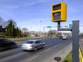 Widok ulicy z radarowym fotoradarem, oznaczeniem prędkości 40 km/h oraz poruszającymi się samochodami.