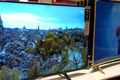 Dwa telewizory na ekspozycji: jeden z panoramą miasta, drugi z postaciami animowanymi.