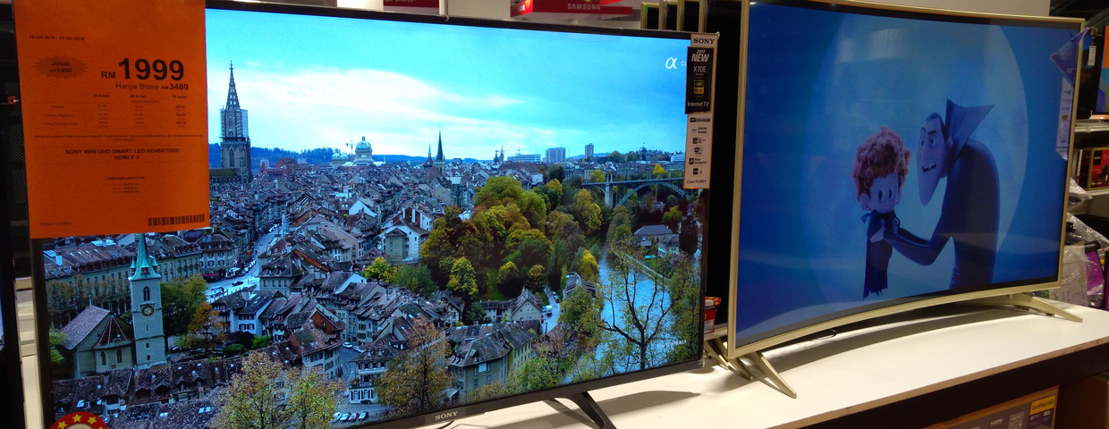 Dwa telewizory na ekspozycji: jeden z panoramą miasta, drugi z postaciami animowanymi.