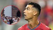 Na zdjęciu widoczny Cristiano Ronaldo w czerwonym stroju, spoglądający w górę, otoczony tłumem.