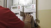 Mężczyzna w czerwonej koszulce obsługuje licznik energii elektrycznej. W tle widoczne dwa liczniki.