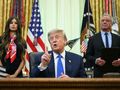 Na zdjęciu Donald Trump, przemawiający przy biurku, z kobietą i mężczyzną w tle.