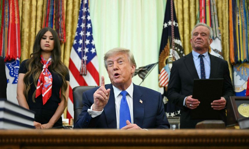 Na zdjęciu Donald Trump, przemawiający przy biurku, z kobietą i mężczyzną w tle.