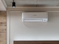Klimatyzator zamontowany na ścianie w nowoczesnym wnętrzu z ceglaną dekoracją.