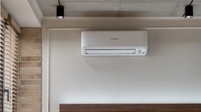 Klimatyzator zamontowany na ścianie w nowoczesnym wnętrzu z ceglaną dekoracją.