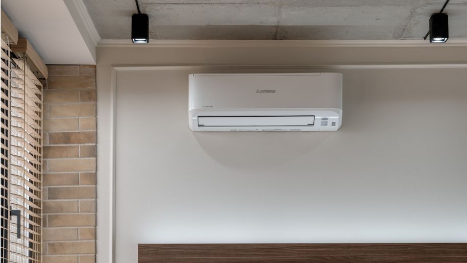 Klimatyzator zamontowany na ścianie w nowoczesnym wnętrzu z ceglaną dekoracją.