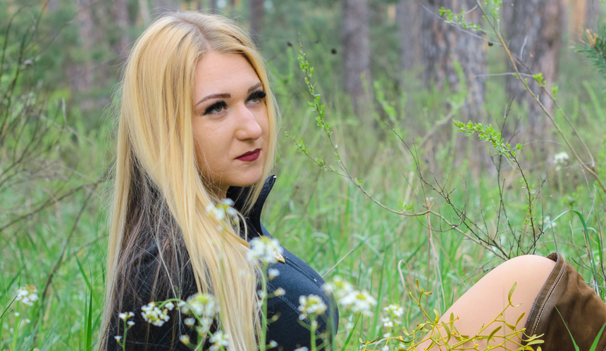 Blondynka siedząca na łące w czarnej bluzie