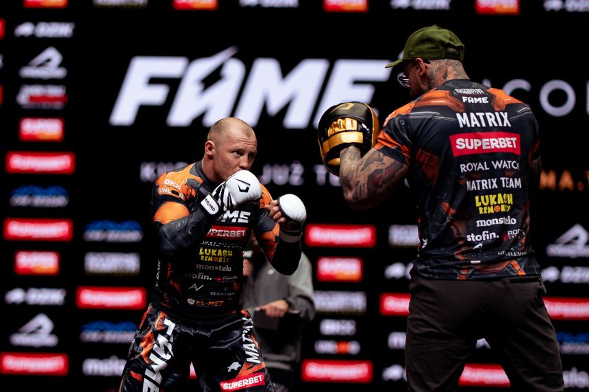 Dwóch zawodników FAME MMA w strojach sportowych, przygotowujących się do walki na tle reklam.