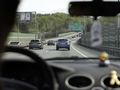 Widok z wnętrza samochodu na autostradę z znakami kierunkowymi do Gdańska i Łodzi.