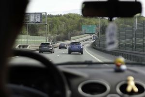 Widok z wnętrza samochodu na autostradę z znakami kierunkowymi do Gdańska i Łodzi.