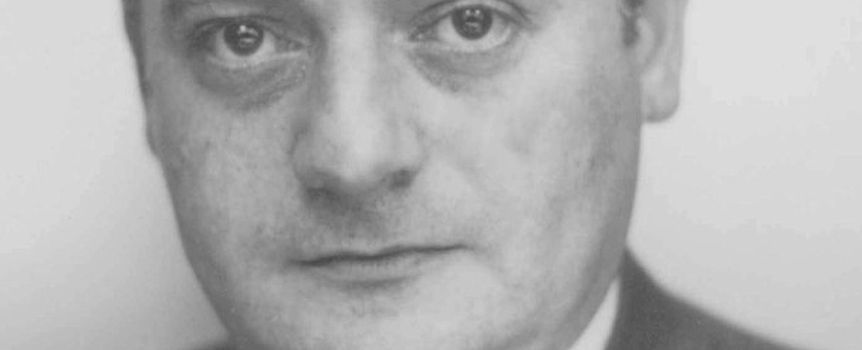 Nie rozpoznaję osoby na zdjęciu. Opis ALT: Zbliżenie na twarz mężczyzny w garniturze, z poważnym wyrazem twarzy.
